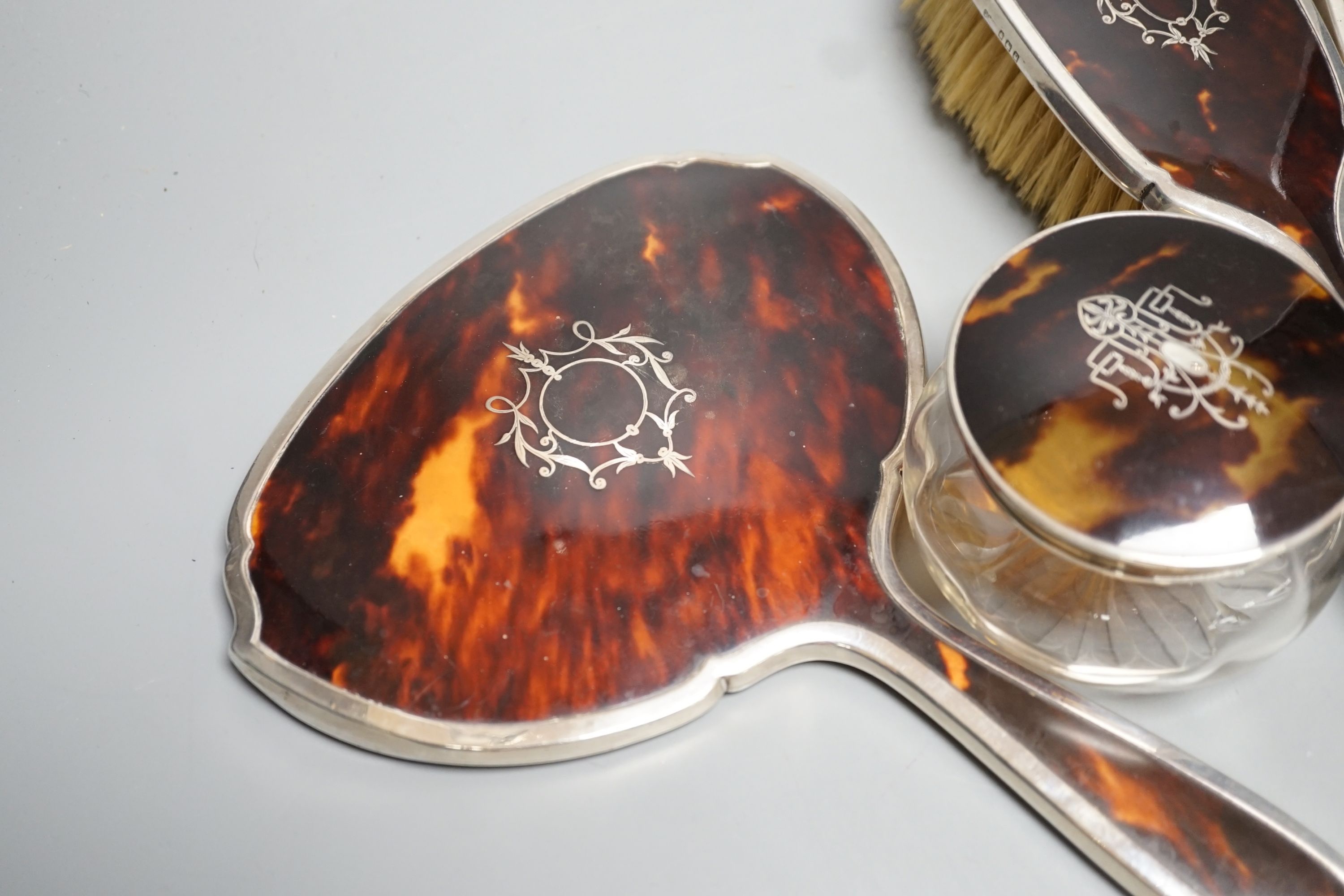 A George V silver and tortoiseshell mounted mirror and brush set, Birmingham, 1928 and a similar powder jar.